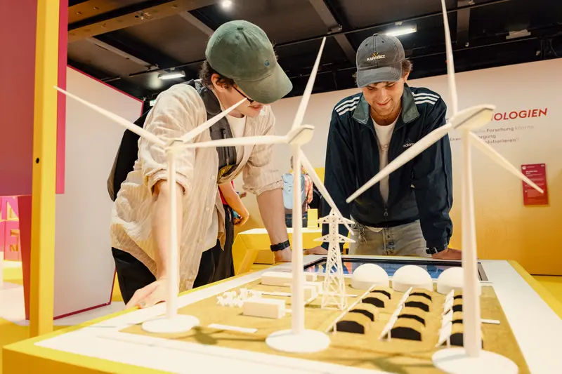 Zwei junge Männer schauen sich das Modell eines Energieparks an.