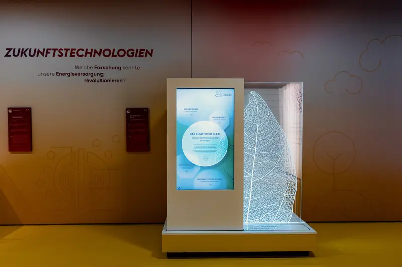 Das Bild zeigt einen großen Bildschirm und das Modell eines Blattes.