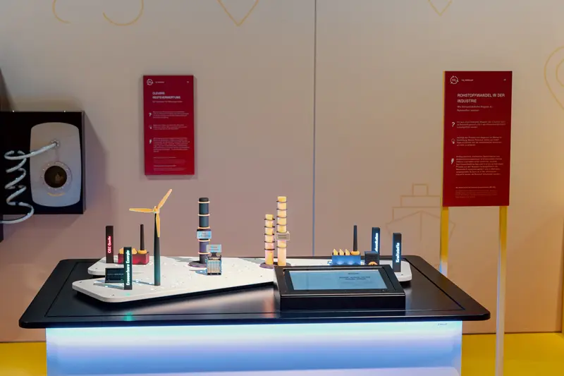 Das Bild zeigt einen Exponatstisch auf dem modellhaft verschiedene Kraftwerke zu sehen sind. Ebenfalls auf dem Tisch zu sehen ist ein Bildschirm.