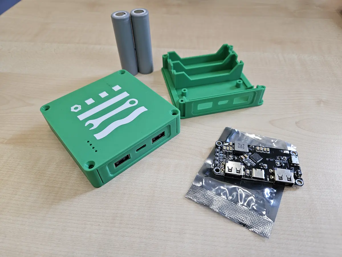 Ein grünes Gehäse einer Poerbank liegt geöffnet neben einem alten Akku